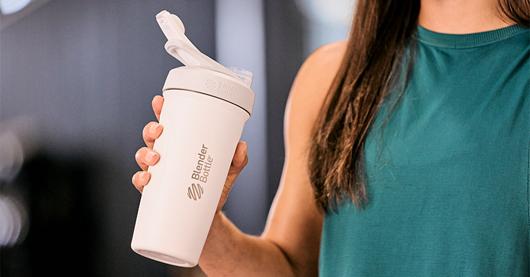 Woman drinking pre workout from an insulated stainless steel Blender Bottle