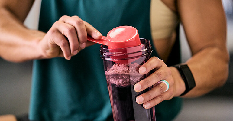Woman putting protein powder into a BlenderBottle Brand Protein Shaker Bottle